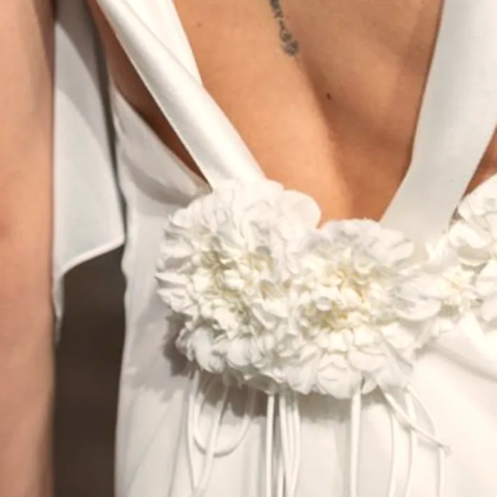 Fiori in tessuto cuciti a mano sulla schiena di un abito da sposa, dettaglio ravvicinato