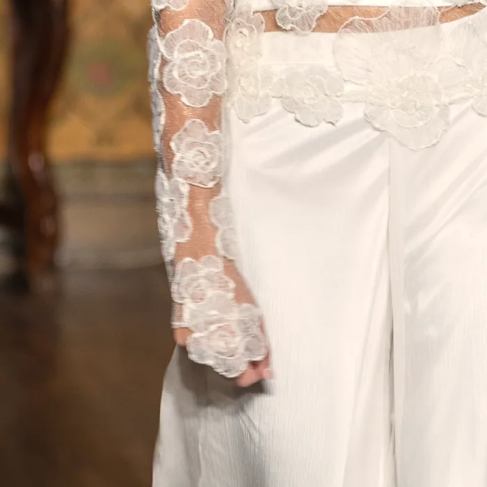 Macro del pizzo con fiori tridimensionali ricamati a mano su un abito da sposa dell’atelier